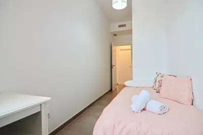 a small room with a pink bed and a desk at Apartamento San Leonardo Playa (Free Parking) in Cádiz