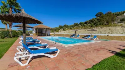 a swimming pool with lounge chairs and an umbrella at Cortijo Escondido Arcos de la Frontera by Ruralidays in Arcos de la Frontera