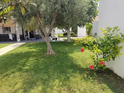 a tree in the middle of a yard with flowers at Chalet con piscina in San Fernando