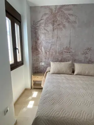 a bedroom with a large bed with a painting on the wall at Villa Tropical a 2 minutos del Faro de Chipiona in Chipiona