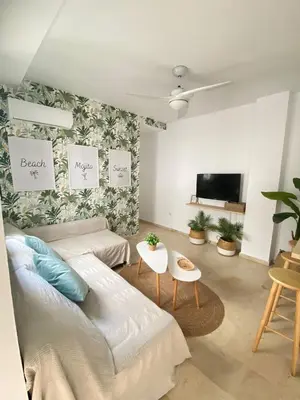 a living room with a couch and a tv at Villa Tropical a 2 minutos del Faro de Chipiona in Chipiona