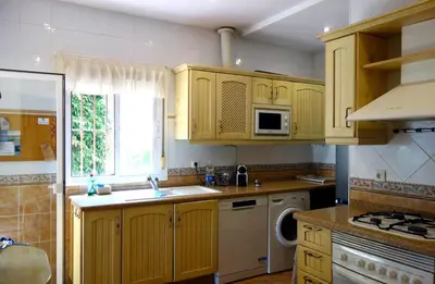 a kitchen with wooden cabinets and a sink and a window at HAPPY HOMES CASA LIMÓN - Premium - Pool - Klimaanlage - WLAN in Chiclana de la Frontera