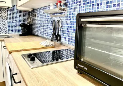 a kitchen with blue tiles on the wall and a microwave at Papallona Cádiz Apartment Grupo AC Gestion in Cádiz