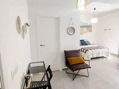 a living room with a chair and a bed at Estudio Mar Azul Grupo AC Gestion in Cádiz