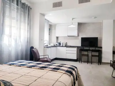 a bedroom with a bed and a kitchen with a table at Estudio Mar Azul Grupo AC Gestion in Cádiz