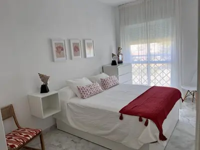 a white bedroom with a bed and a window at Apartamento Any en Rota in Rota