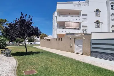a building with a fence and a bench in the grass at Apartamento Any en Rota in Rota