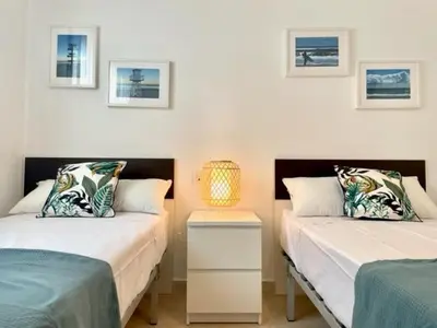 a bedroom with two beds and a table with a lamp at GATU PREMIUM El Viñedo, centro, parking, aire acc, terraza, piscina comun
