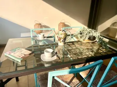 a glass table with two blue chairs and a glass table with cups at GATU PREMIUM El Viñedo, centro, parking, aire acc, terraza, piscina comun