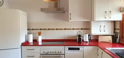 a kitchen with red counter tops and white cabinets at Appartement à 850 m de la plage de la Barrosa in Chiclana de la Frontera