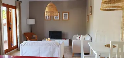 a living room with white chairs and a television at Appartement à 850 m de la plage de la Barrosa in Chiclana de la Frontera