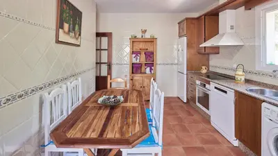 a kitchen with a wooden table and white appliances at Villa Lola 14 Chiclana de la Frontera by Ruralidays in Chiclana de la Frontera