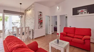 a living room with a red couch and a table at Villa Bananera Conil de la Frontera by Ruralidays in Conil de la Frontera