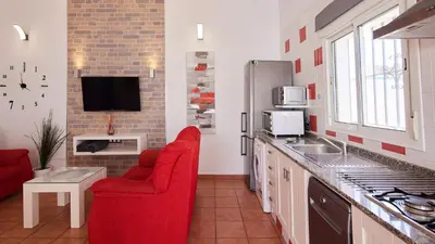a kitchen with two red chairs and a tv in it at Villa Bananera Conil de la Frontera by Ruralidays in Conil de la Frontera