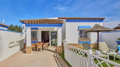 a white house with a patio with a table and an umbrella at Villa Yuca Conil de la Frontera by Ruralidays in Conil de la Frontera