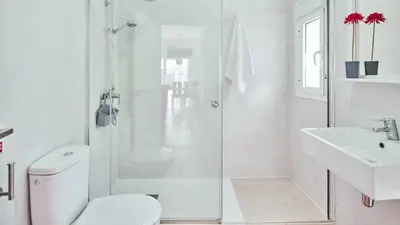 a white bathroom with a shower and a toilet and a sink at Villa Yuca Conil de la Frontera by Ruralidays in Conil de la Frontera