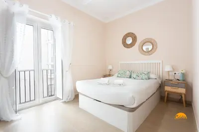 a white bedroom with a bed and a window at Corralon de los Carros by Cadiz Time in Cádiz