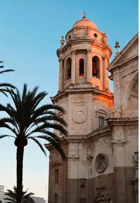 an old building with a clock tower with a palm tree at Mar Vendaval Grupo AC Gestion in Cádiz