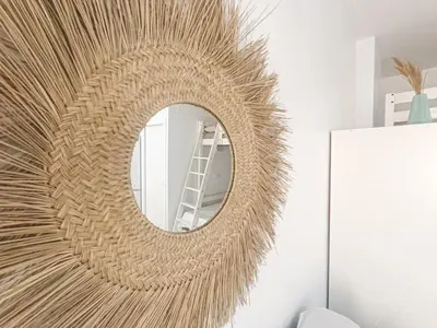 a rattan mirror on a wall in a room at Puerto Sherry Boat in El Puerto de Santa María