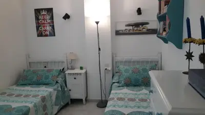 a bedroom with two beds and a floor lamp at Wehostcostaluz -Apartamento El Parador in El Puerto de Santa María