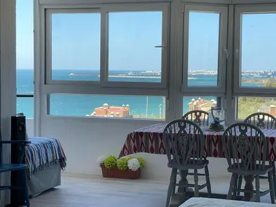 a dining room with a table and chairs and the ocean at Wehostcostaluz -Apartamento El Parador in El Puerto de Santa María
