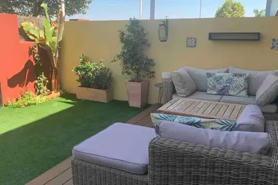 a patio with a wicker couch and a table at Sanlúcar Bajo de Guía PG Apartamentos in Sanlúcar de Barrameda