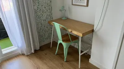 a small desk with a green chair next to a window at Sanlúcar Bajo de Guía PG Apartamentos in Sanlúcar de Barrameda