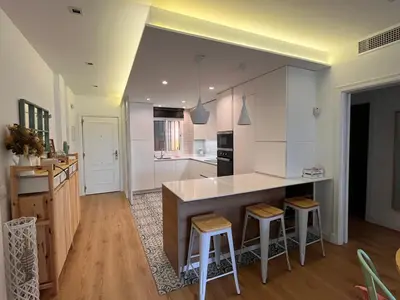 a kitchen with white cabinets and a island with bar stools at Sanlúcar Bajo de Guía PG Apartamentos in Sanlúcar de Barrameda