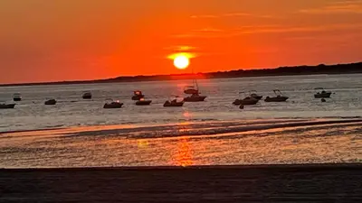 a group of boats in the water at sunset at Sanlúcar Bajo de Guía PG Apartamentos in Sanlúcar de Barrameda