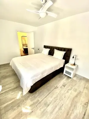 a bedroom with a large bed with a ceiling fan at Apartamento en el centro San Fernando Cadiz. in San Fernando