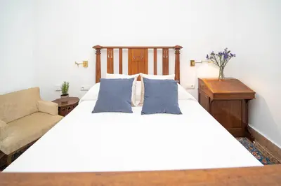 a bedroom with a large white bed and a couch at La Casa 1832 Boutique in Sanlúcar de Barrameda