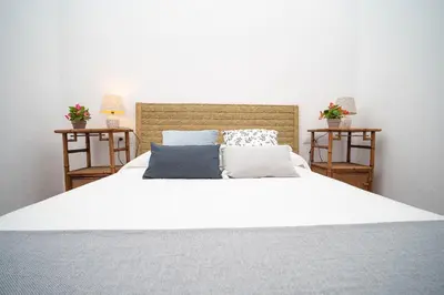 a bedroom with a white bed with two side tables at La Casa 1832 Boutique in Sanlúcar de Barrameda