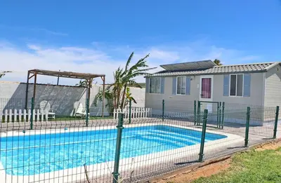 a fence around a swimming pool in front of a house at Bungalow Puntalejo in Conil de la Frontera