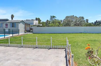 a fence in front of a yard with a house at Bungalow Puntalejo in Conil de la Frontera