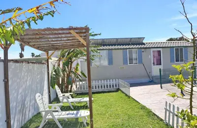 a backyard with two white chairs and a pergola at Bungalow Puntalejo in Conil de la Frontera