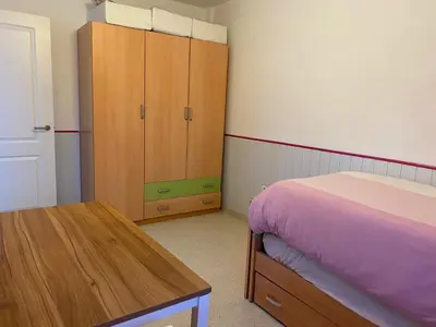 a bedroom with a bed and a wooden cabinet at Casa Ohana in Conil de la Frontera