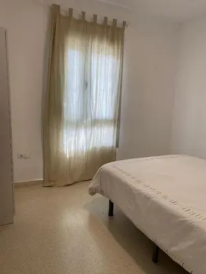 a bedroom with a bed and a window with curtains at Casa Ohana in Conil de la Frontera