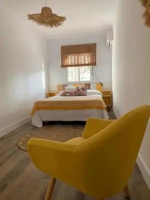 a bedroom with a bed and a yellow chair at Apartamento en la Barrosa in Chiclana de la Frontera