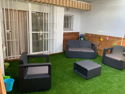 a patio with green grass and furniture on it at Apartamento en la Barrosa in Chiclana de la Frontera