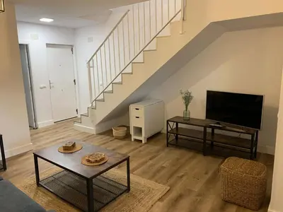 a living room with a couch and a tv and stairs at Apartamento en la Barrosa in Chiclana de la Frontera