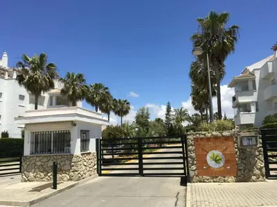 a house with a fence and palm trees in the background at Ático Costa Ballena - Cádiz in Rota
