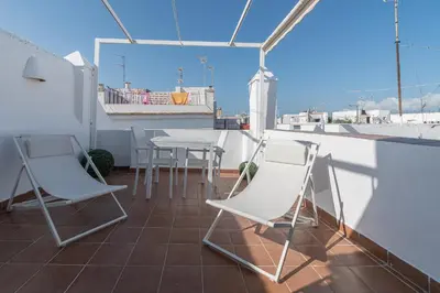 a balcony with chairs and a table on a roof at Terraza Estampa de Cádiz in Cádiz