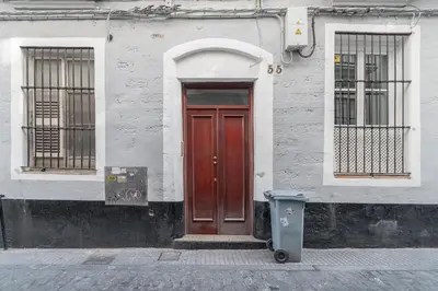 a building with a red door and a trash can at Terraza Estampa de Cádiz in Cádiz