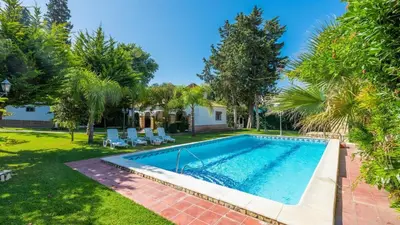 a swimming pool in a yard with palm trees at Villa Las Carmenes Conil de la Frontera by Ruralidays in Conil de la Frontera