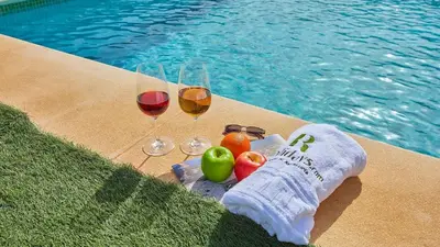 two glasses of wine and fruit next to a swimming pool at Cortijo de Liche Arcos de la Frontera by Ruralidays in Arcos de la Frontera
