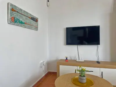 a living room with a table and a flat screen tv at Villa Nostos - Ole Solutions in Cádiz