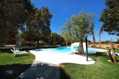 a swimming pool in a park with a tree at Hacienda Laguna Seca - Apart. Hibisco in Chiclana de la Frontera