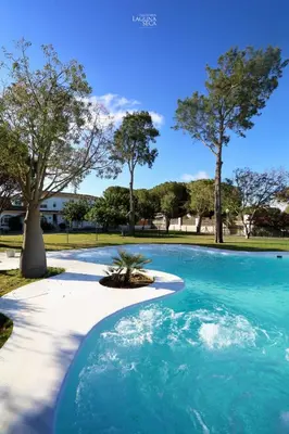 a swimming pool with blue water in a park at Hacienda Laguna Seca - Apart. Hibisco in Chiclana de la Frontera