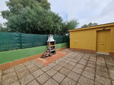a backyard with a brick fireplace next to a fence at Chalet a 2 kilometros de la playa in Chiclana de la Frontera