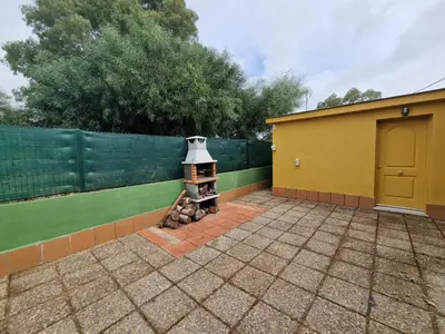 a backyard with a brick fireplace next to a fence at Chalet a 2 kilometros de la playa in Chiclana de la Frontera